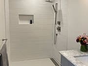 Tiled walk-in shower beside a vanity edge with flowers